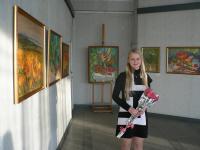 Анна  Хандожко на фоні експозиції власних творів